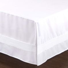 a white bed skirt on a wooden floor