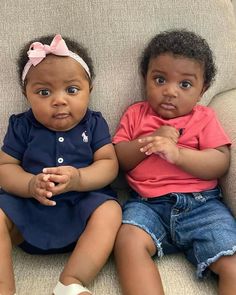 two children sitting on a couch with one looking at the camera and the other staring