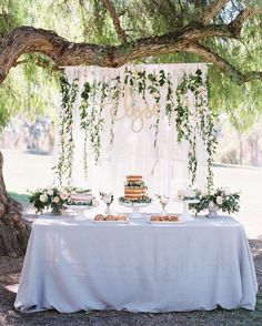 an image of a table set up for a wedding reception with flowers and greenery