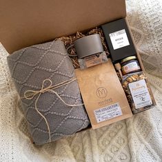 an open box with some items in it on a white blanket next to a brown bag