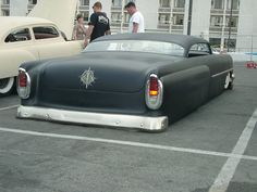 an old black car parked in a parking lot