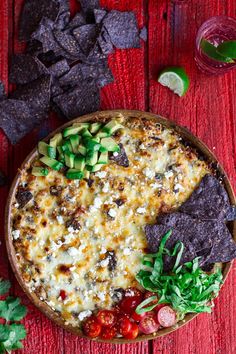 a bowl filled with nachos and chips on top of a red wooden table