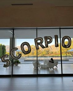 a large balloon that says scorpion in front of a glass wall with chairs and tables