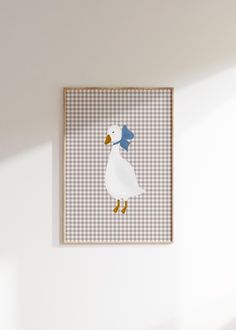 a white duck with a blue hat on it's head hanging from a wall