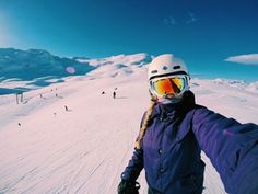 a person on skis standing in the snow with their arms out and wearing goggles