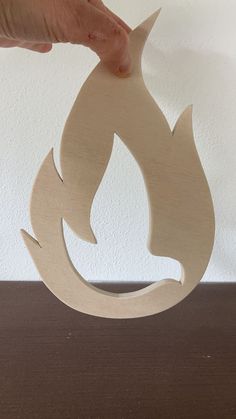 a person holding a piece of wood that has been cut into shapes with the shape of a fire