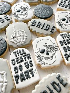 decorated cookies with black and white frosting on a wooden surface, including one for bride and the other for grooms