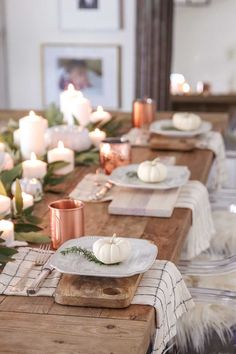 the table is set with white pumpkins and candles