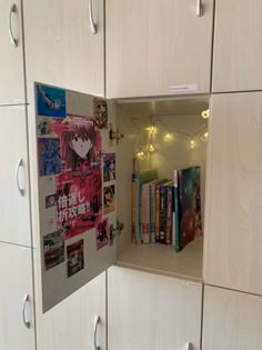 an open book shelf filled with lots of books next to white cupboards covered in magnets