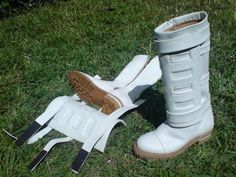 a pair of white boots sitting on top of a lush green grass covered field next to each other