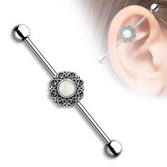 an ear piercing with opal and filigrees in the middle, on top of a white background