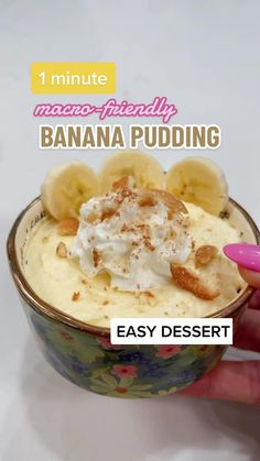 a banana pudding in a bowl with whipped cream and cinnamon on top, being held up by a woman's hand