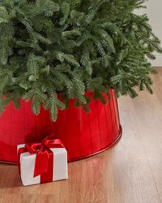 a christmas tree in a red bucket with a bow