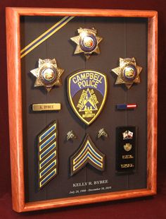 a wooden framed display with badges and pins on it's front side, including the words campbell police