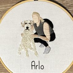 a cross stitched picture of a woman and her dog with the word arlo on it