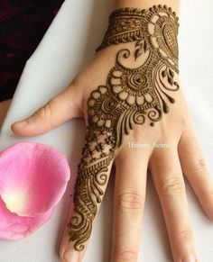 a henna on someone's hand next to a flower