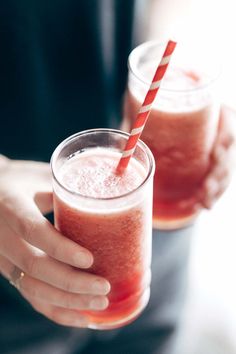 two people are holding glasses with drinks in them, one is red and the other is pink