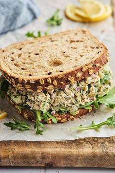 a sandwich with lettuce, meat and other toppings sits on a cutting board