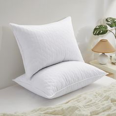 a white pillow sitting on top of a bed next to a lamp