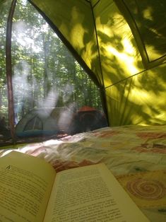 an open book sitting on top of a bed next to a tent