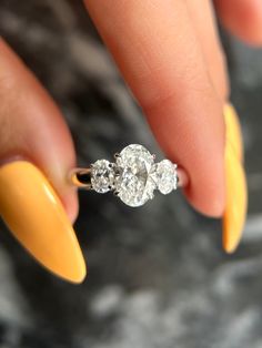 a woman's hand with yellow nails and an engagement ring on top of her finger