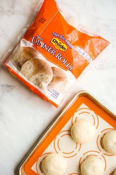 rolls are sitting on a baking sheet next to a bag of dinner rolls in a pan