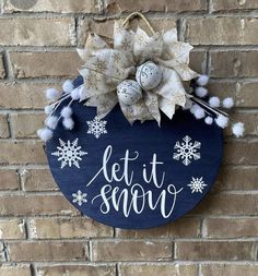 a sign that says let it snow on the side of a brick wall with pom poms