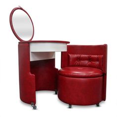 a red chair sitting next to a table with a mirror on it