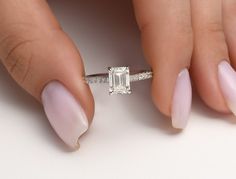 a woman's hand holding a ring with a diamond on it and two fingers