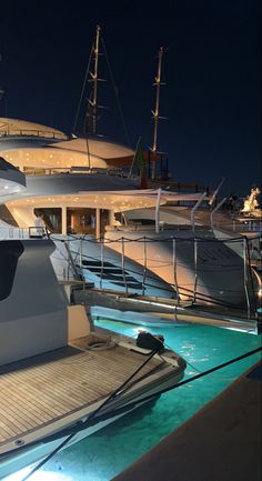 several yachts are docked at night with lights on the deck and in the water