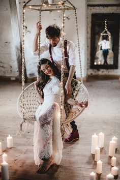 a man and woman sitting in a swing chair surrounded by candles