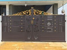 an iron gate with decorative designs on the top and bottom, in front of a house