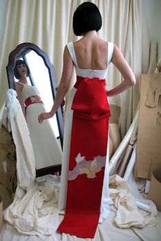 a woman standing in front of a mirror wearing a red and white dress