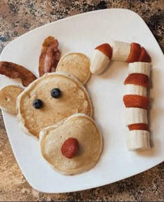 a white plate topped with pancakes, bacon and a face made to look like a reindeer