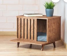 a small wooden cabinet with a plant in it and a book on the top shelf