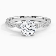 a white gold engagement ring with diamonds on the band and a round cut diamond in the center