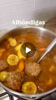 someone is cooking some meatballs and vegetables in a pot on the stove with a ladle