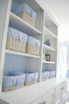 a baby's nursery room with blue and white accessories on shelves, including baskets