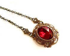 Beautiful victorian style pendant necklace made of a lovely oxidized brass filigree cabochon base, American made, and a vintage ruby red rhinestone cabochon. The size of the cabochon is 13 x 18 mm. The necklength is approximately 49 cm. (19.3 inches) For more jewelry please visit our shop: http://www.minouc.etsy.com For combined shipping please contact us. We also combine shipping with our other Etsy shop where we sell vintage fabrics and finds from Holland and France: http://www.minoucbrocante. Antique Red Brass Jewelry, Red Ruby Victorian Necklace, Red Oval Victorian Necklace, Victorian Brass Necklace For Valentine's Day, Vintage Filigree Necklace For Valentine's Day, Victorian Antique Gold Necklaces For Valentine's Day, Victorian Antique Gold Necklace For Valentine's Day, Antique Red Filigree Jewelry, Antique Red Oval Pendant Jewelry