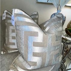 two decorative pillows are on display in a room with other furniture and decor items behind them