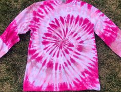 a pink and white tie - dyed shirt laying on the grass