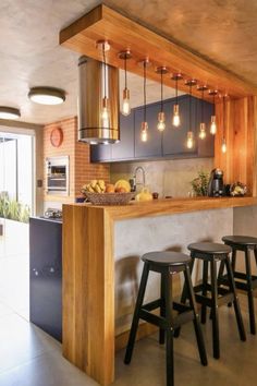 a kitchen with three stools in front of the counter and lights hanging from the ceiling