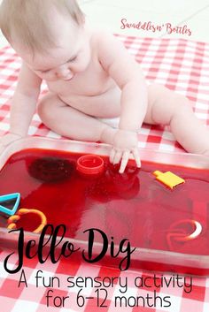 a baby playing with a red tray filled with toys on top of a checkered table cloth