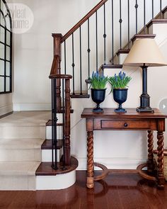 a wooden table with two vases on top of it next to a stair case