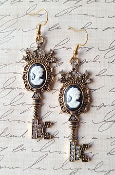 Add some elegance and a hint of romance to your accessory collection. The keys with cameo silhouette are encrusted with diamond-like crystals, swirl designs, and a white on black silhouette cameo lady. The earrings are created of goldtone plated precious metals and hypoallergenic ear hooks. These earrings will surely be the key to any onlooker's heart. Length: 3 inches Width: .75 inches  Purchases will be shipped within 3-5 business days, unless requested otherwise. Packages are shipped via USPS Elegant Cameo Earrings As Gift, Elegant Cameo Earrings For Gift, Vintage Charm Earrings For Wedding, Cameo Drop Earrings For Gifts, Vintage Charm Drop Earrings As Gift, Elegant Cameo Dangle Earrings, Vintage Charm Drop Earrings For Gift, Elegant Cameo Metal Jewelry, Elegant Vintage Charm Drop Earrings