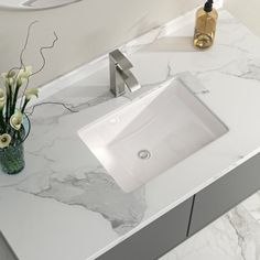 a bathroom sink sitting on top of a counter next to a vase with flowers in it