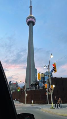 a tall tower with a sky scraper in the background and people walking around it