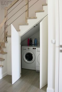 there is a washer and dryer in this small room with stairs leading up to the second floor