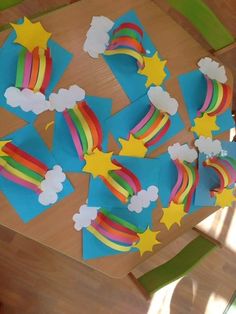 some paper cut out with rainbows and stars on them sitting on a wooden table