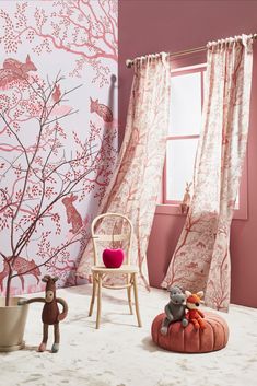 a room with pink walls, curtains and stuffed animals on the floor in front of a window